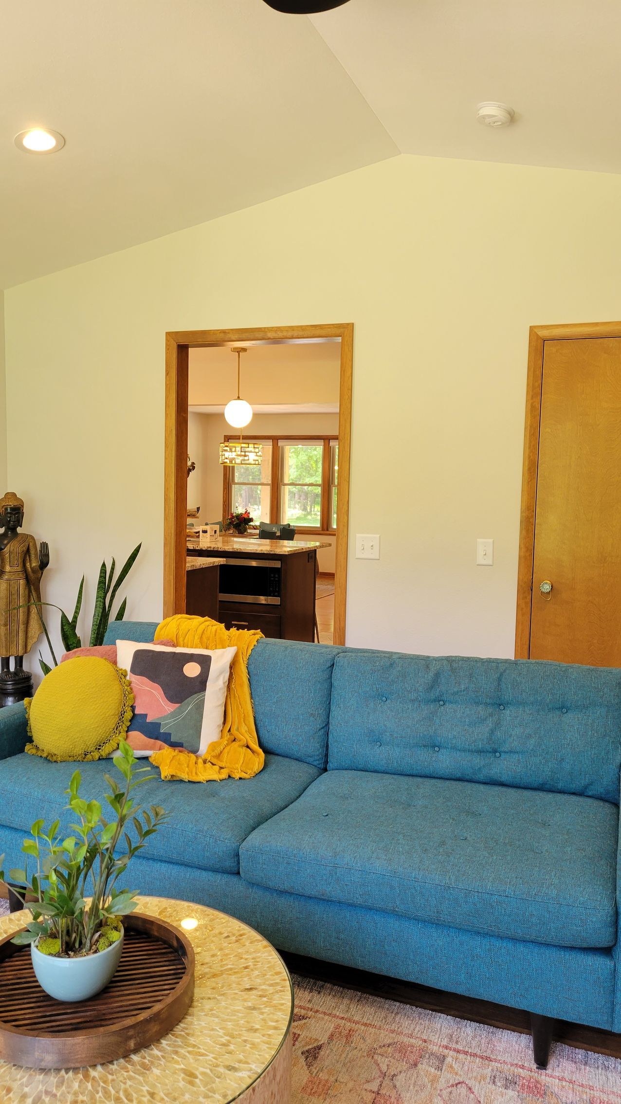 Blue couch in a living room, with a view into a kitchen.