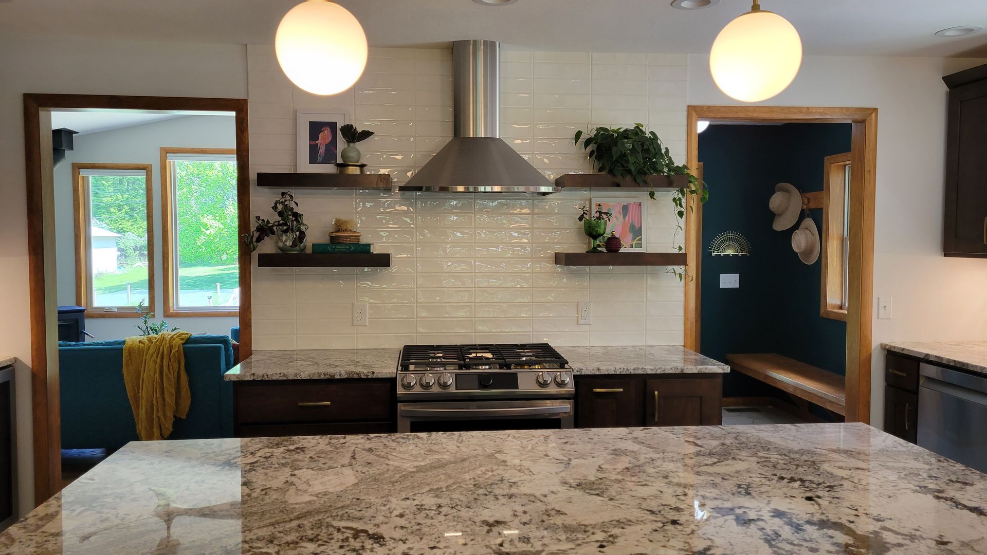 Kitchen with stove, backsplash, shelves, and granite countertops. Two doorways and hanging globe lights are visible.