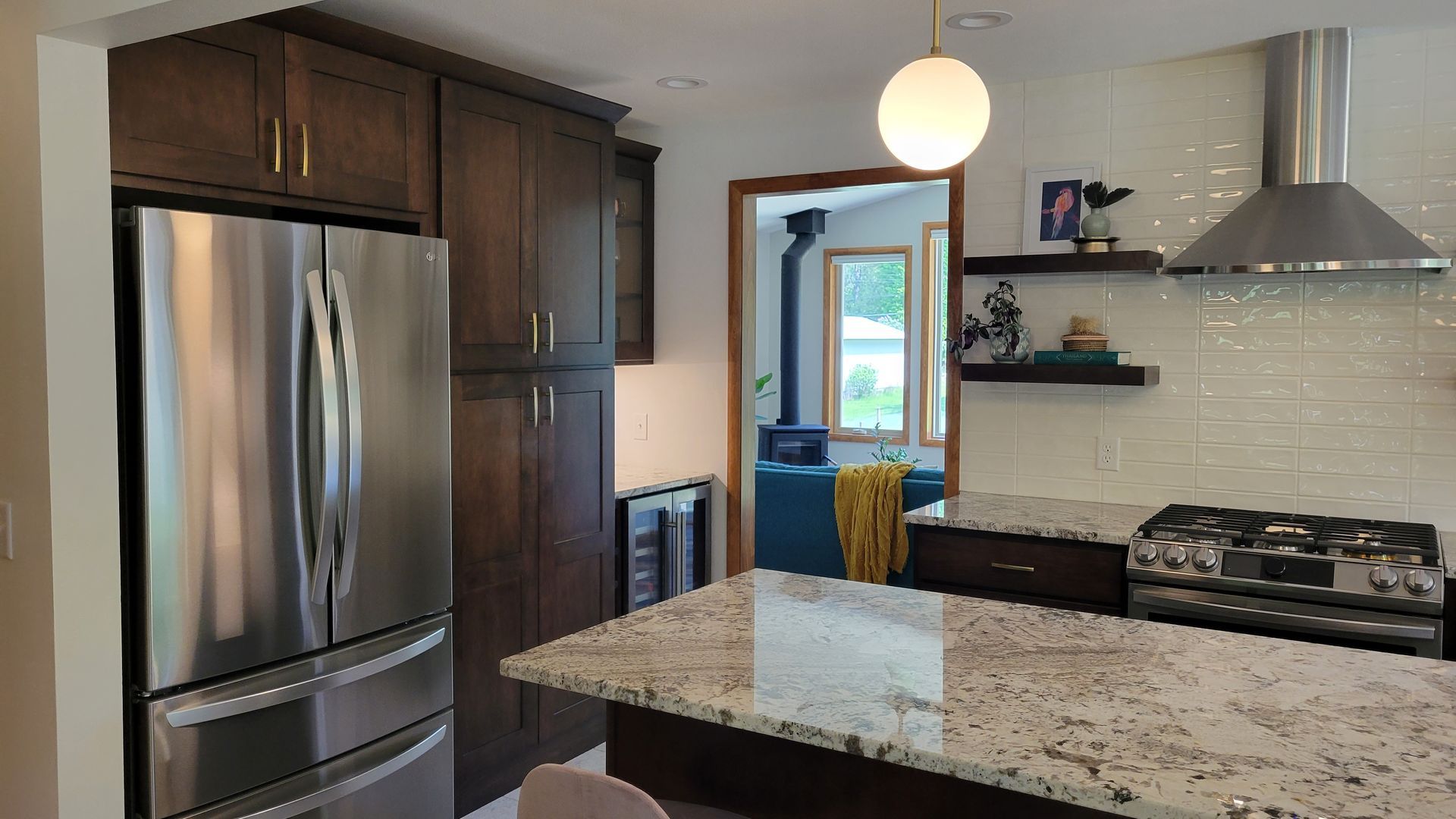 Modern kitchen with dark cabinets, stainless steel appliances, and a granite countertop island.