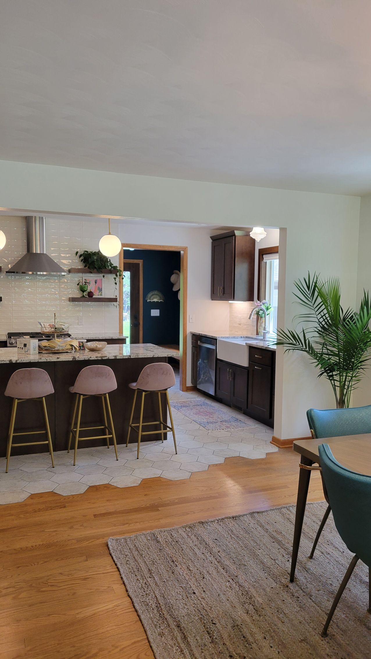Kitchen with brown cabinets, island with stools, and dining table with blue chairs.