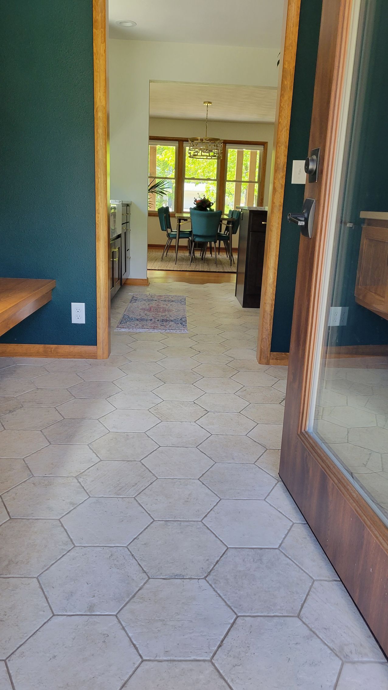 Hallway with hexagon tile floor, open door, leading to a room with desk and windows.