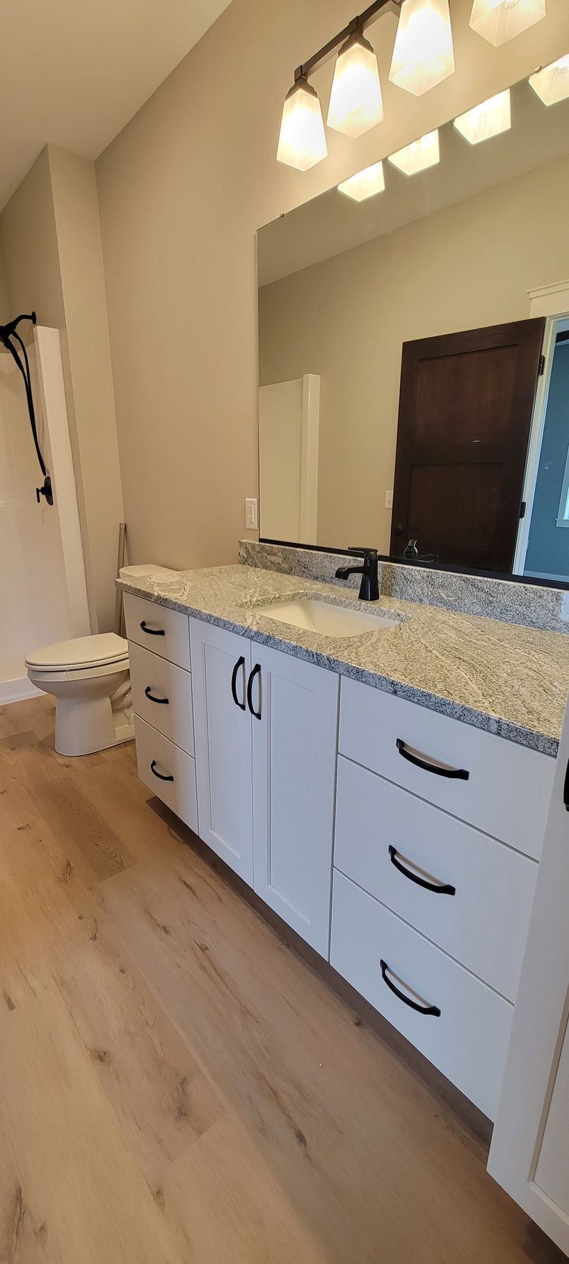 Bathroom with white cabinets, light countertop, mirror, and a toilet.