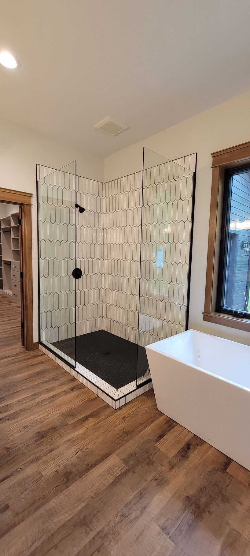Bathroom with a walk-in shower, freestanding tub, and wooden floors.