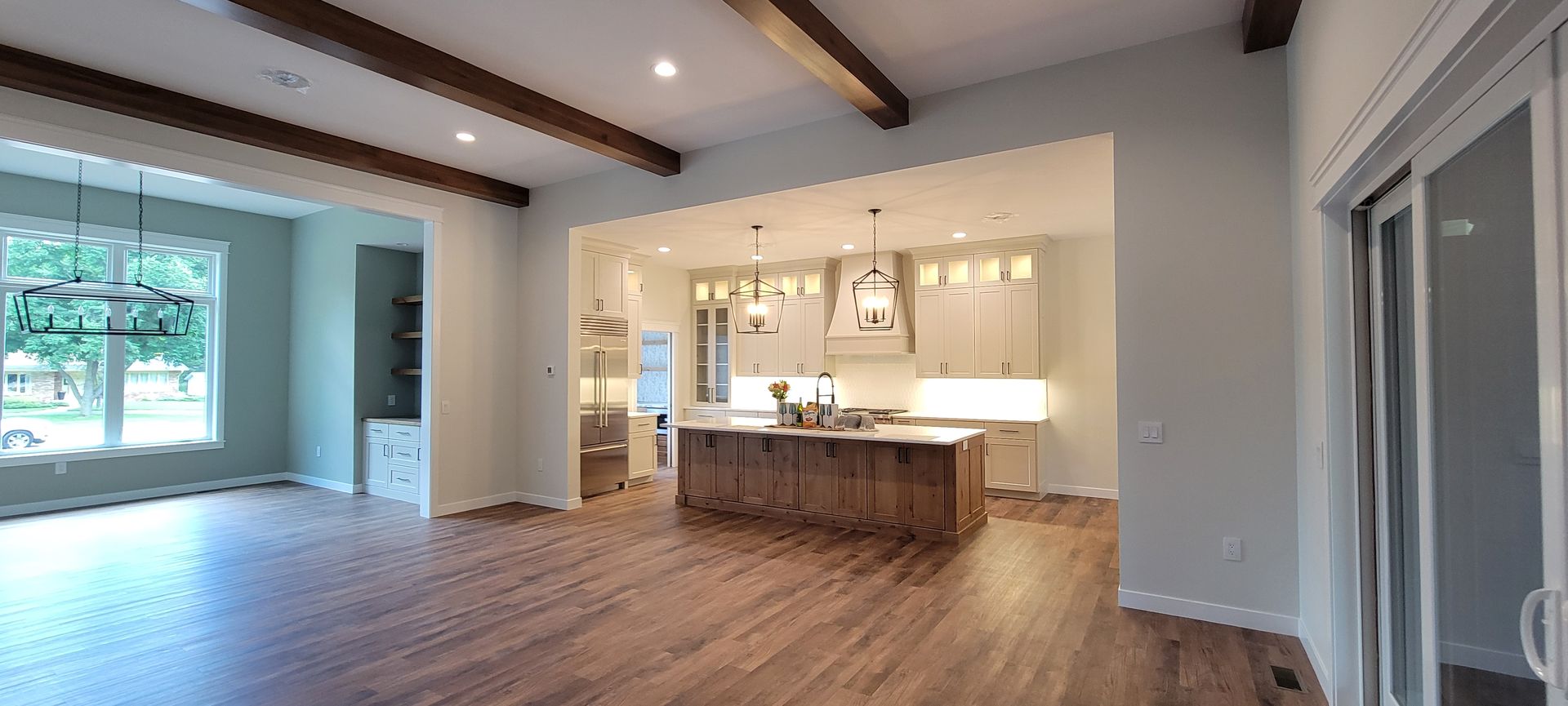Interior view of a modern kitchen with a wooden island, light cabinets, and hardwood floors.