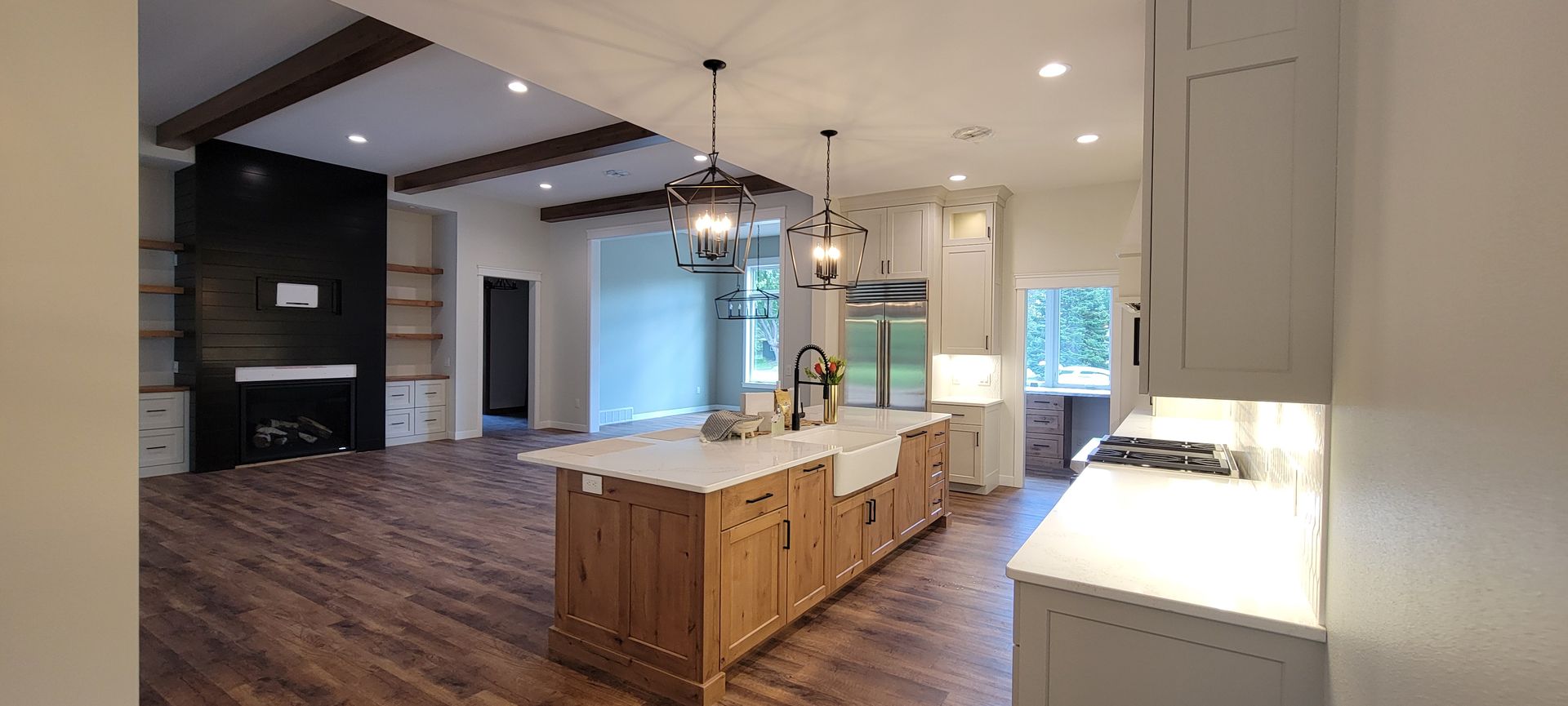 Spacious kitchen with a large island, wood floors, and a black fireplace wall.