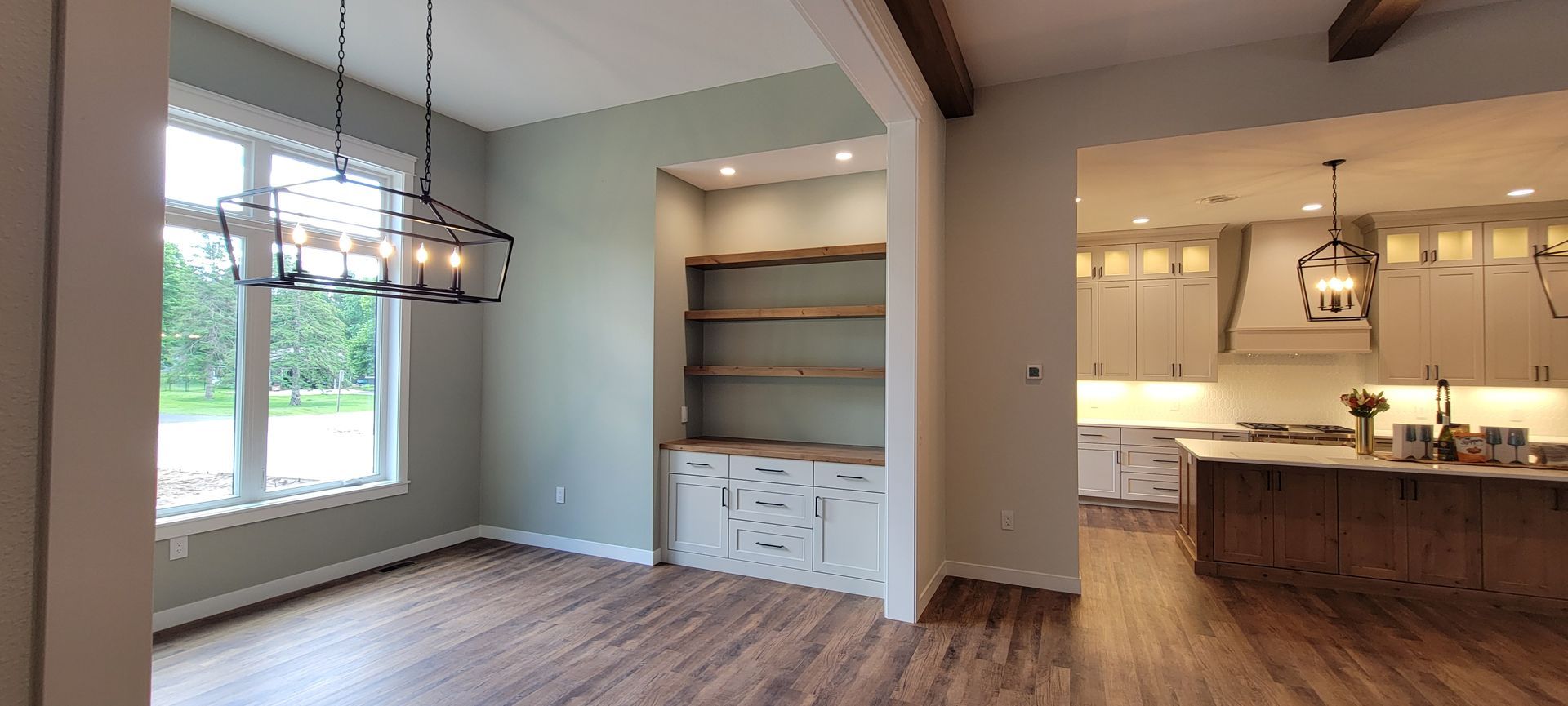Interior view of a dining room with built-in shelves and an open kitchen concept.