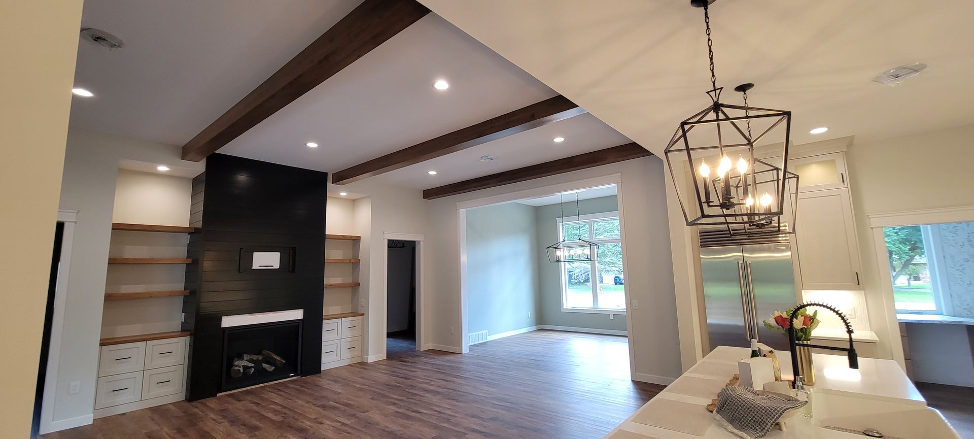 Interior view of a living room with wooden beams on the ceiling, a fireplace, and a hanging light fixture.