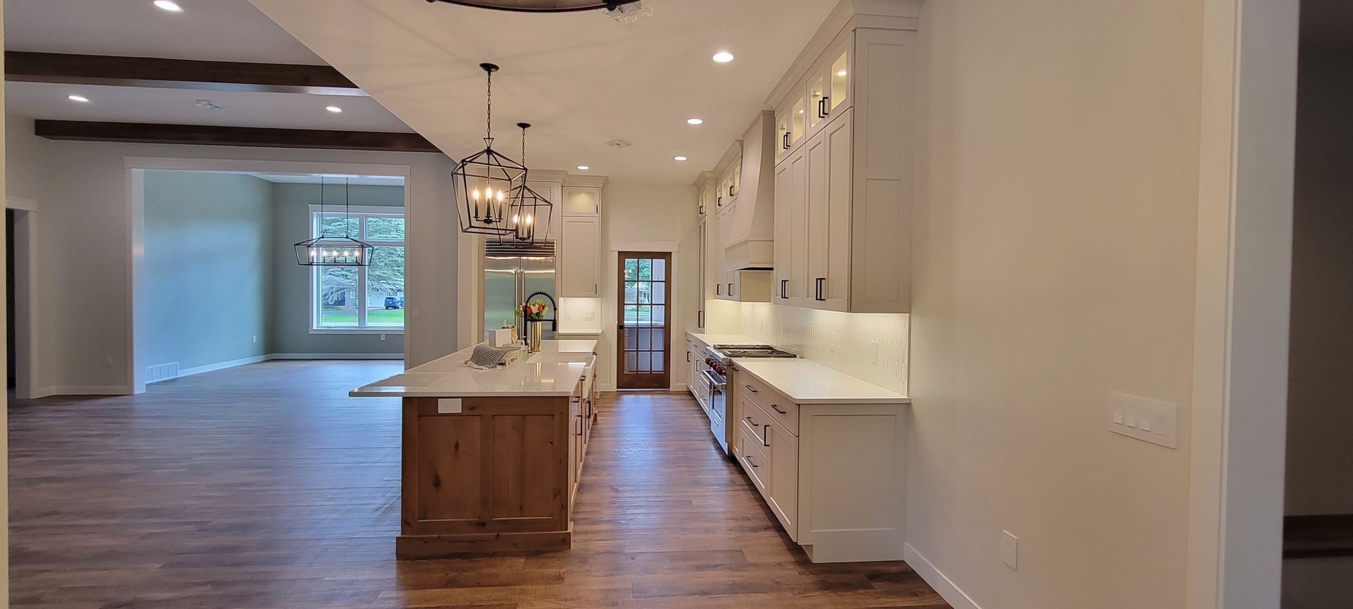 Modern kitchen with light cabinets, wooden island, and open-plan living space.