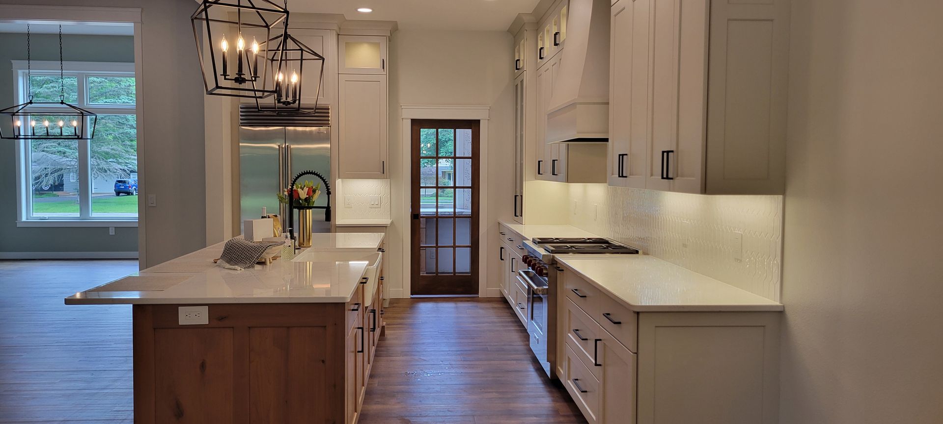 A modern kitchen with a large island, stainless steel appliances, and wood cabinets.