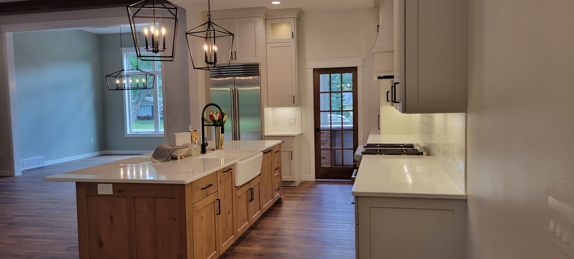 Kitchen with island, light wood cabinets, white countertops, and open doorway.