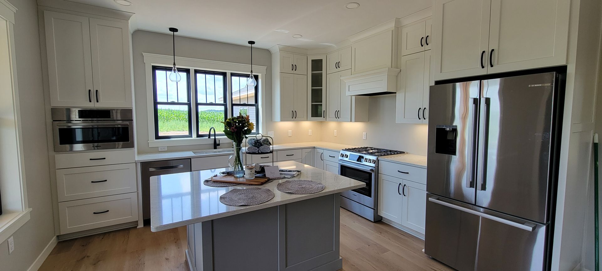 A bright, modern kitchen with white cabinets, stainless steel appliances, and a gray island.