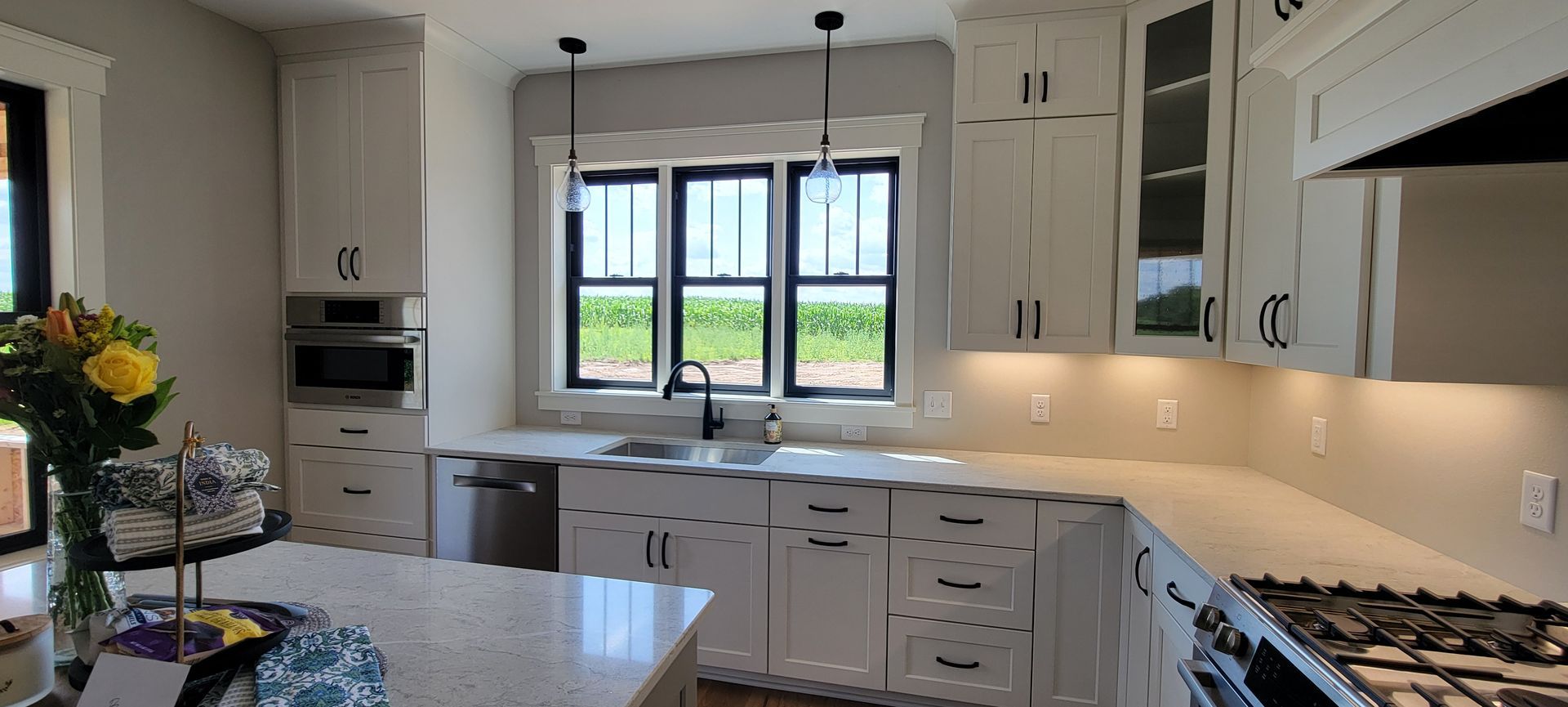 White kitchen with cabinetry, countertops, and appliances, featuring a large window.