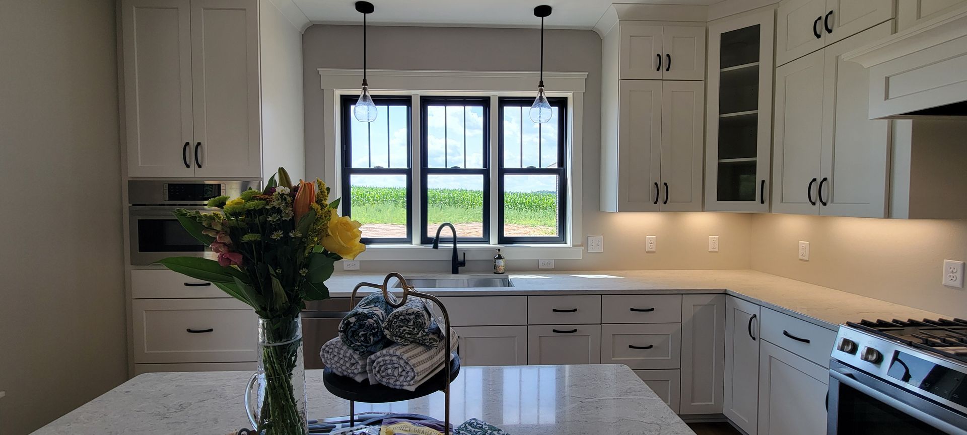White kitchen with island, cabinets, and a window overlooking a field.