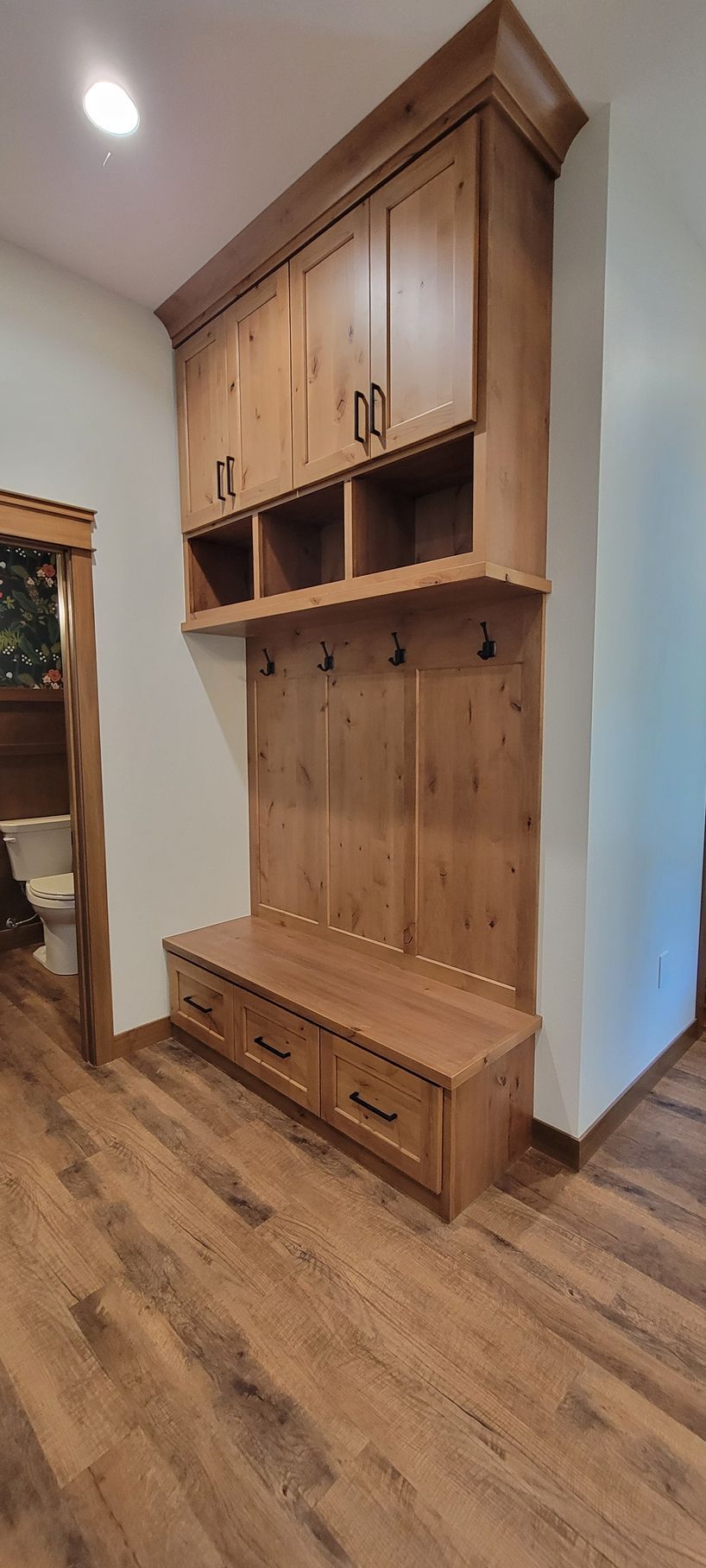 Wooden entryway storage unit with bench and drawers; hooks and cubbies above.