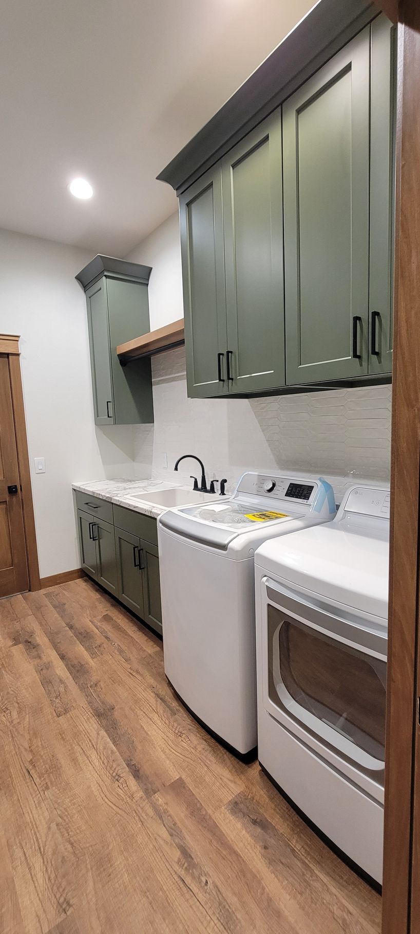 Kitchen with a large island, white cabinets, and dark wood flooring. Two lantern pendant lights hang.