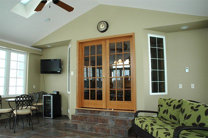 Living room with wood-framed double doors, wall-mounted TV, and green patterned sofa