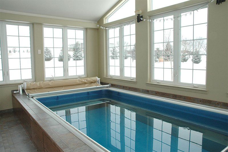 Indoor swimming pool with blue water and large windows overlooking snow-covered trees