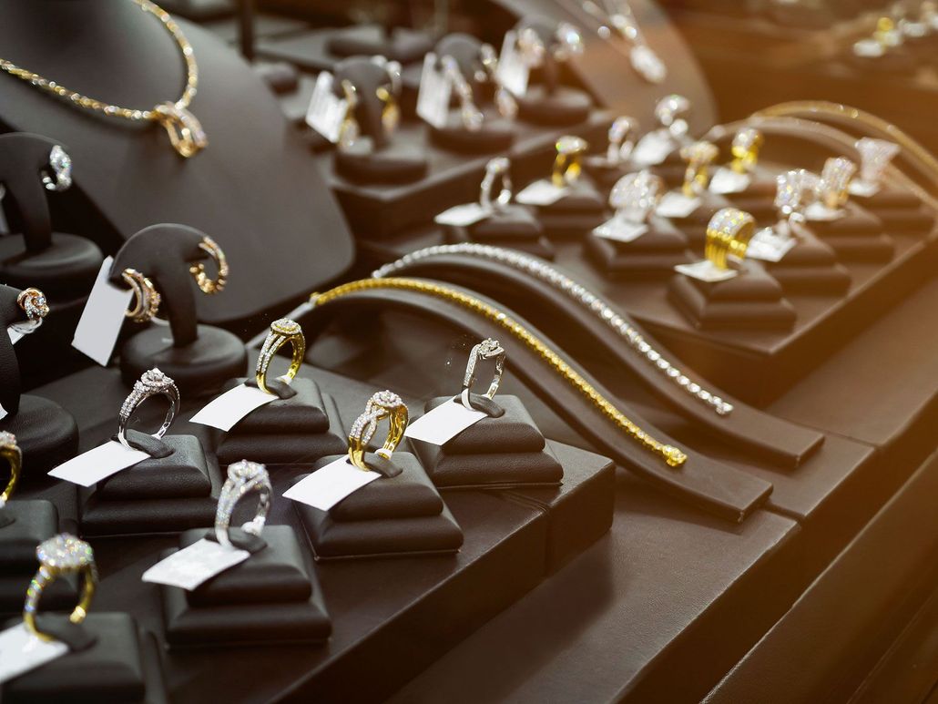 Jewelry display case with rings, bracelets, and necklaces on black stands, with price tags.