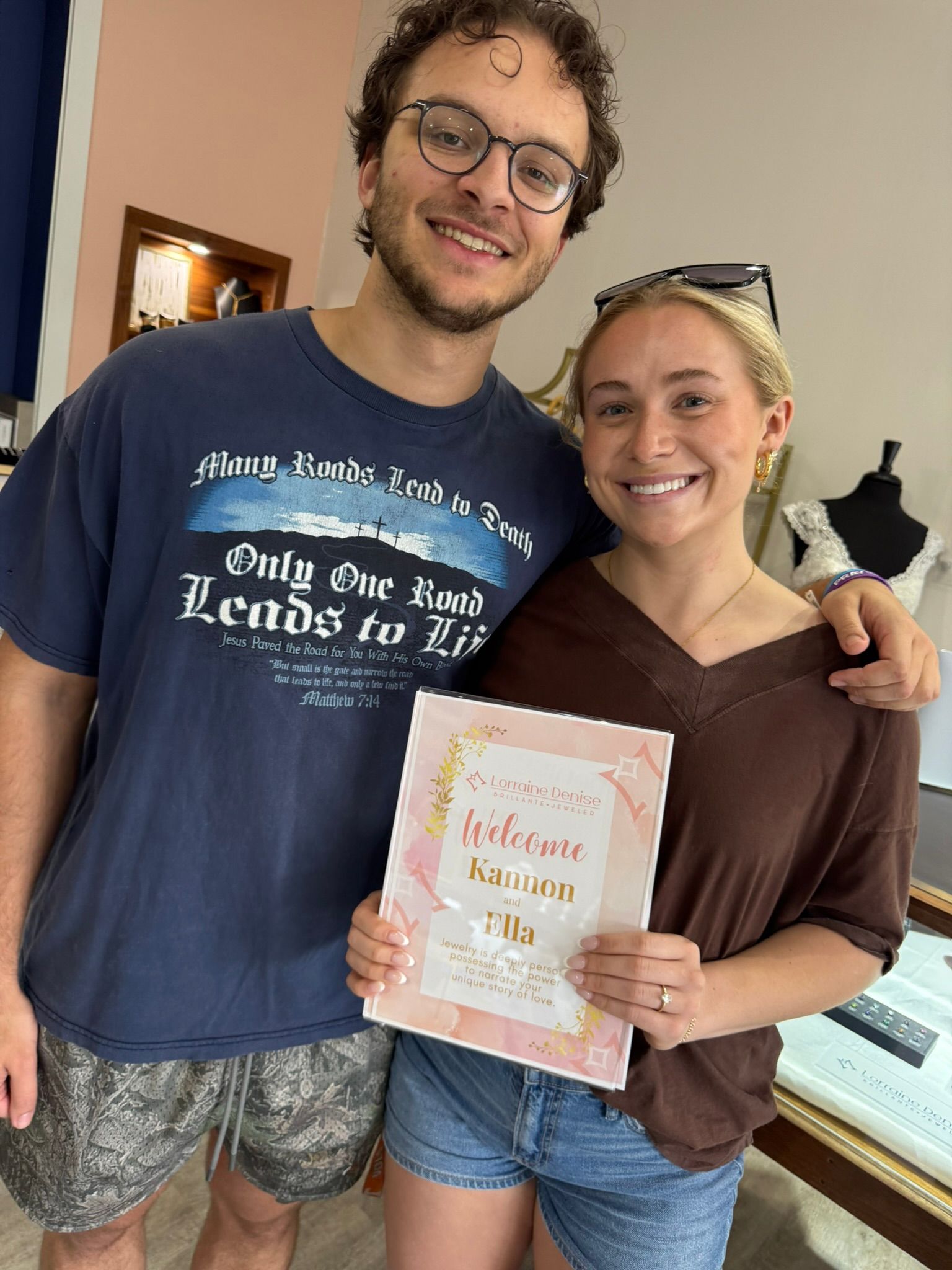 Smiling couple holding a pastel-colored sign indoors