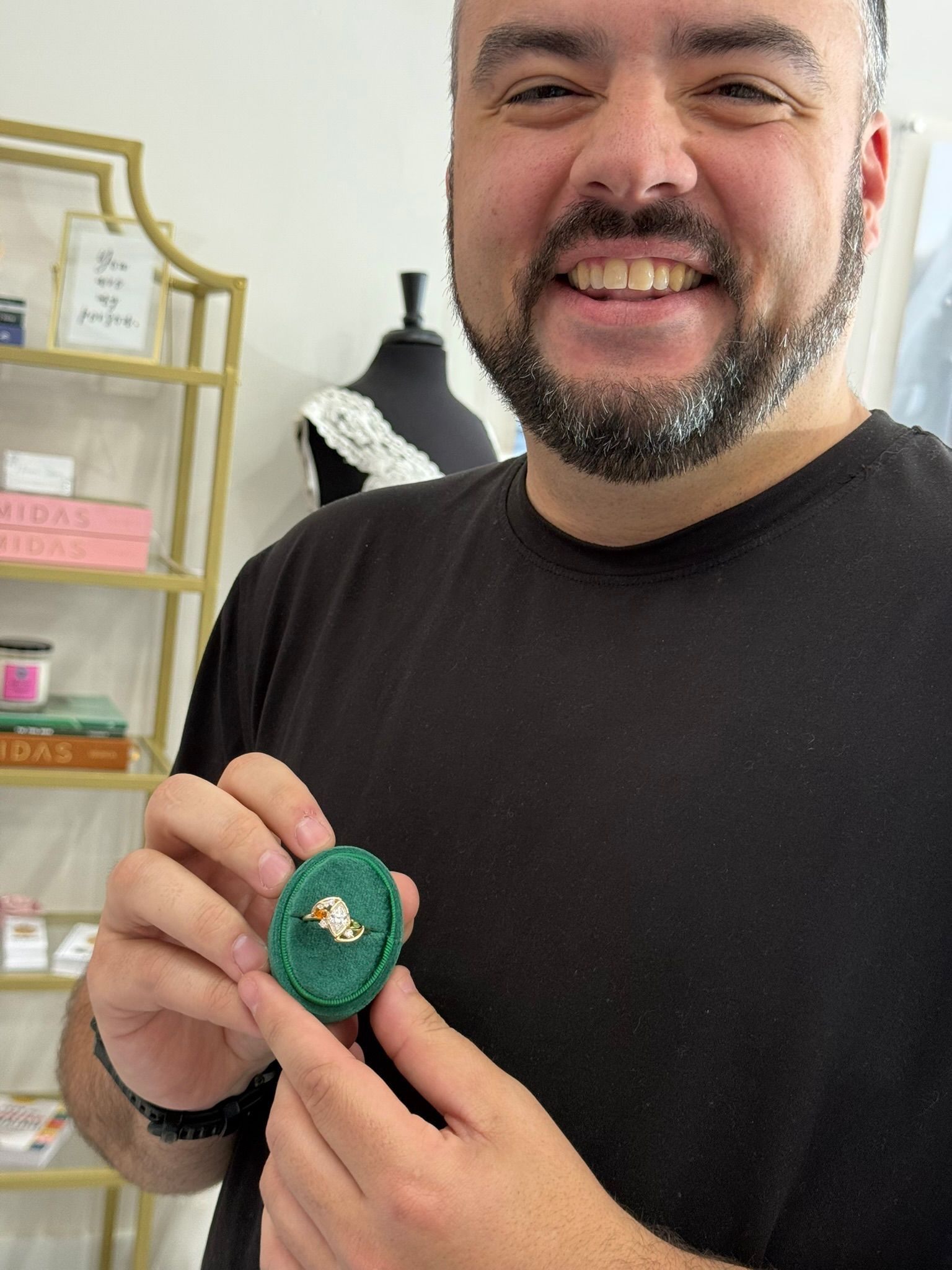 Smiling man in black shirt holding a ring
