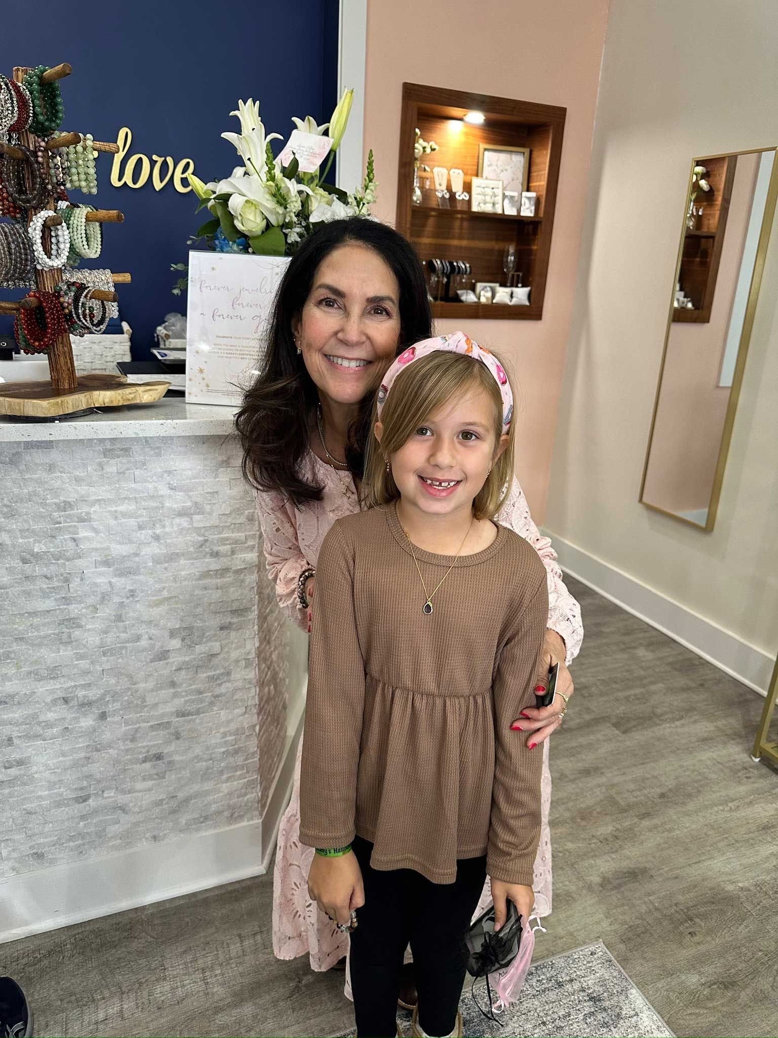 Woman and child smiling indoors beside a decorated table and mirror