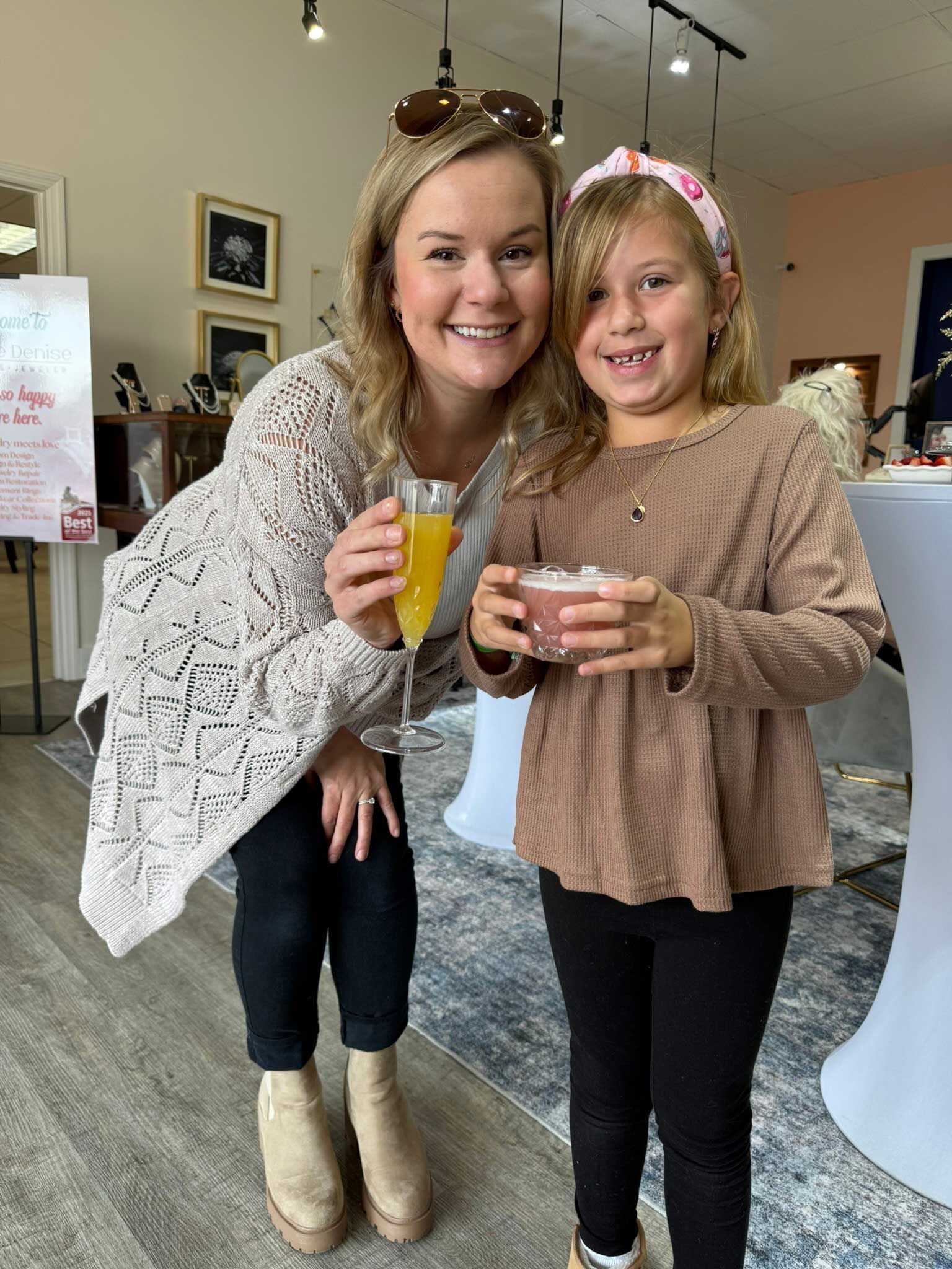 Two people smiling indoors, holding drinks at a cafe-like event