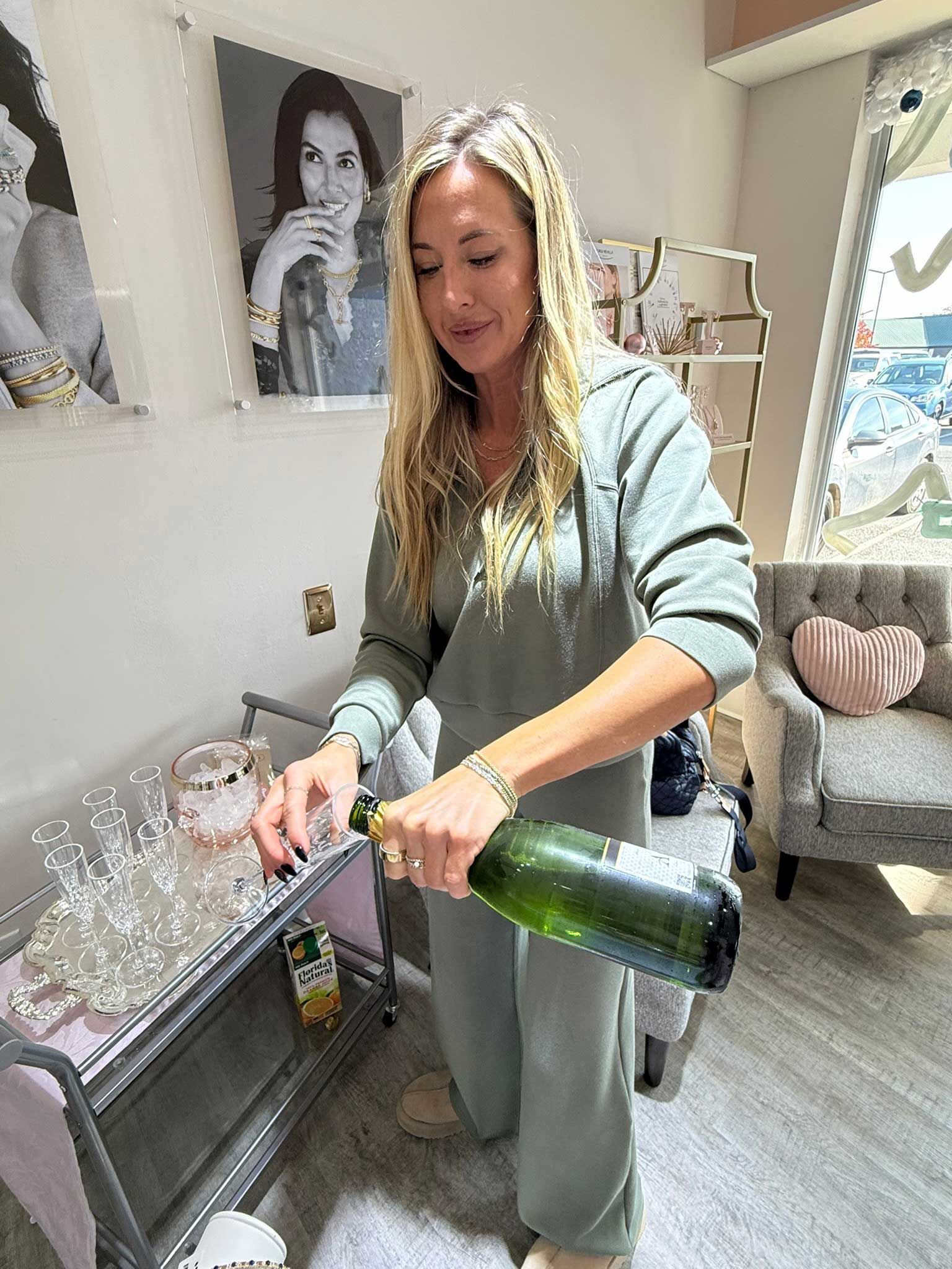 Woman opening a champagne bottle in a bright room with glasses and décor nearby