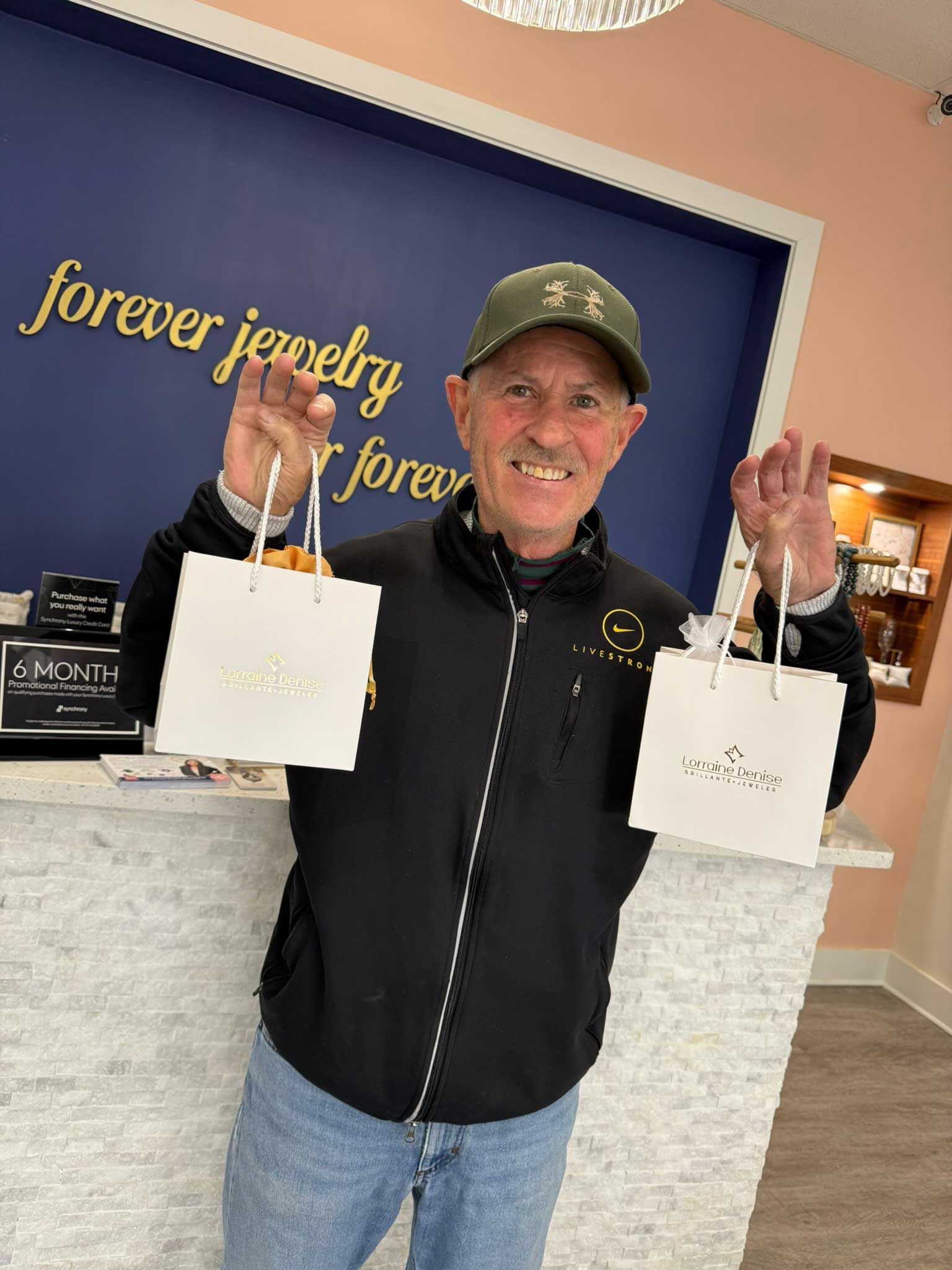 Smiling man holding two white bags in a jewelry store.
