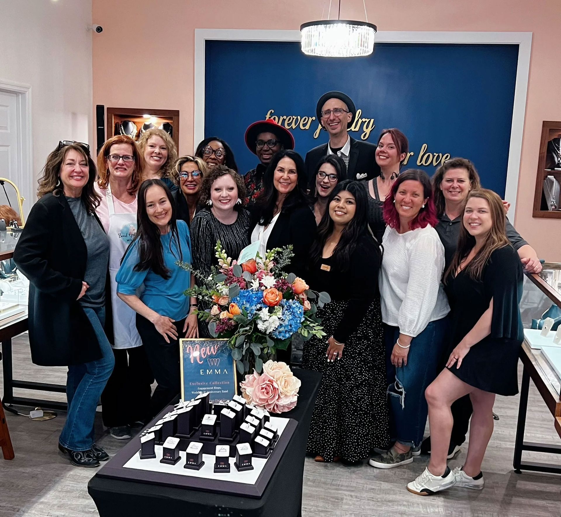 Group of people at Forever Jewelry store with jewelry display and sign.