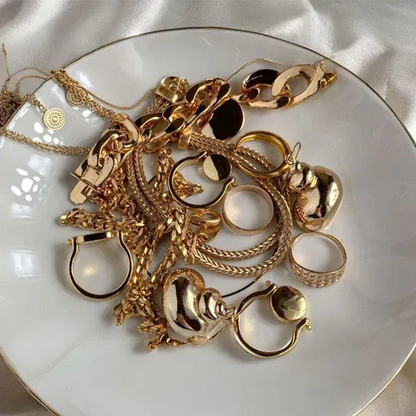 Jewelry display case filled with rings and earrings on white stands, some gold, some silver.