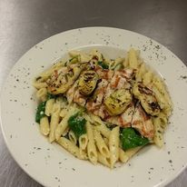 A plate of pasta with chicken and vegetables on a table