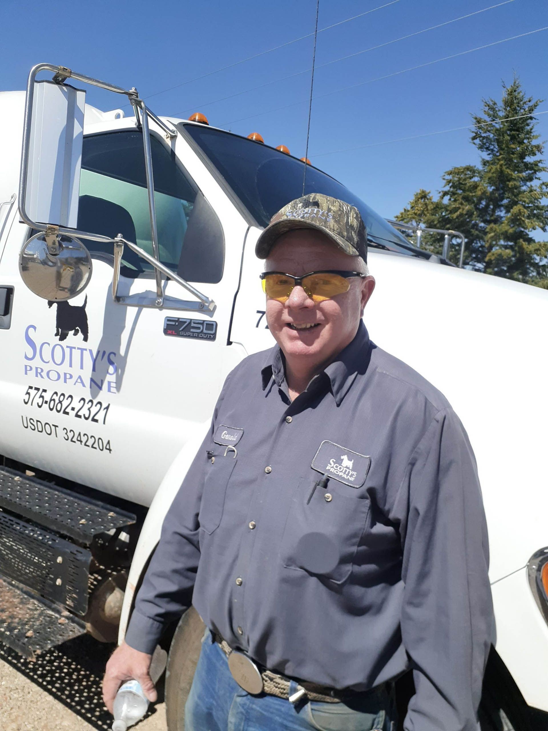 A man is standing in front of a Scotty's Propane truck.