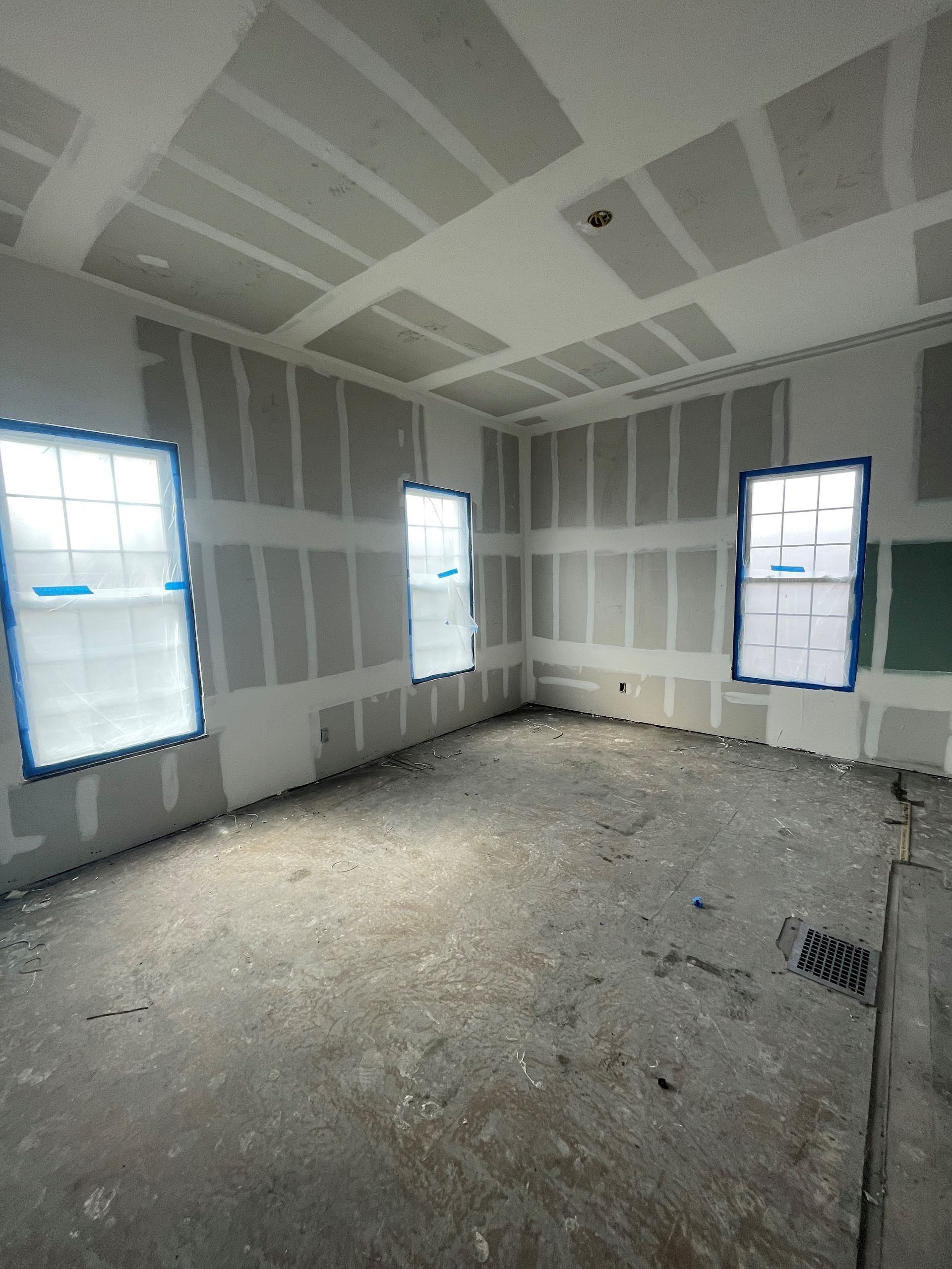 A room that is being remodeled with a lot of windows and drywall