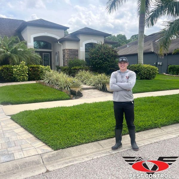 A man is standing in front of a house with his arms crossed