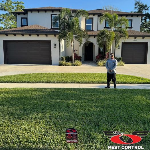 A man is standing in front of a large house.