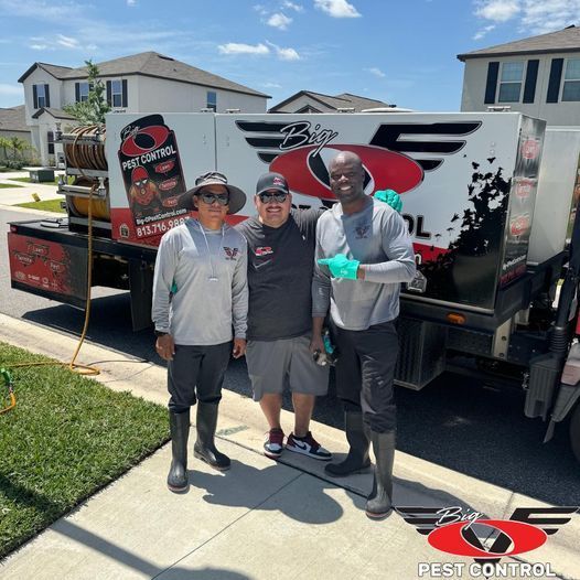 Three men standing in front of a truck that says pest control
