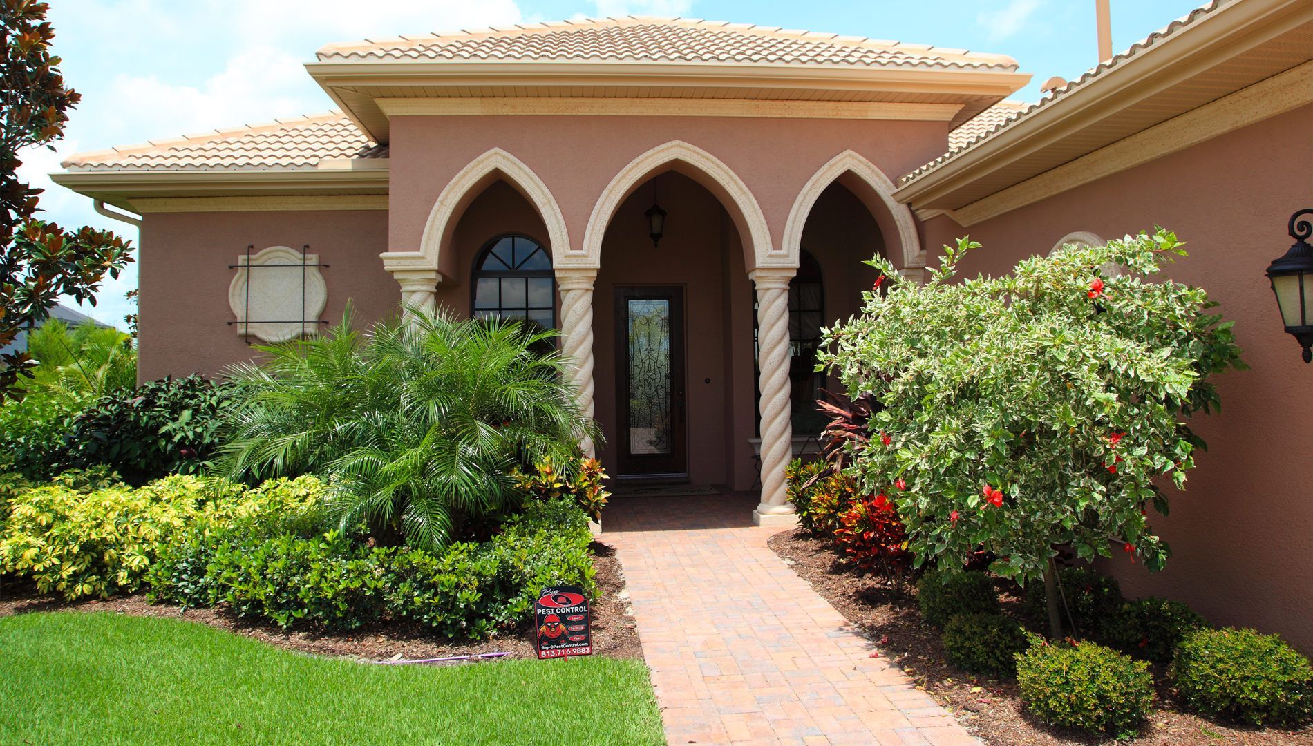 A large house with arches and a brick walkway leading to it
