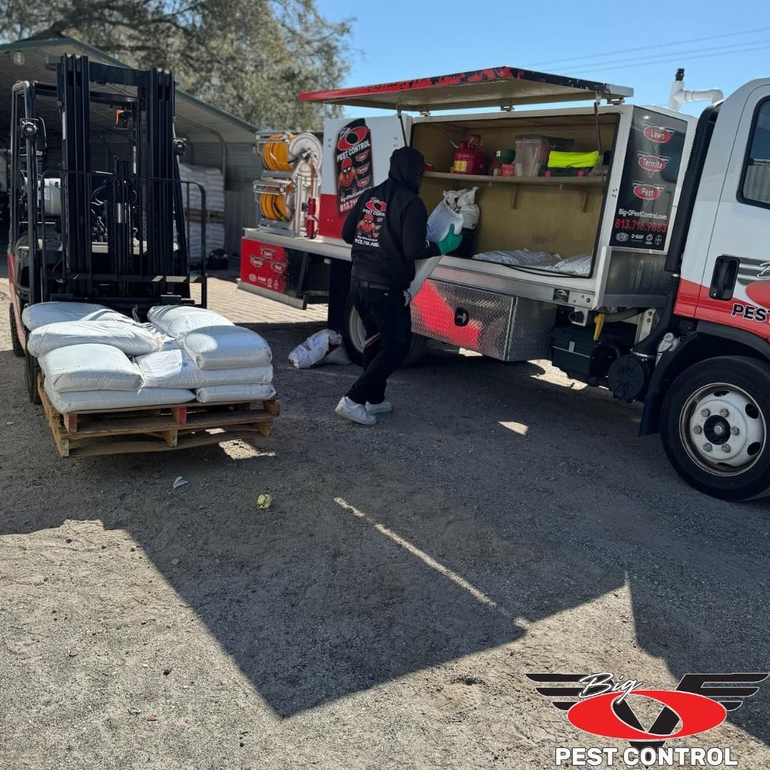 A pest control truck is parked next to a forklift