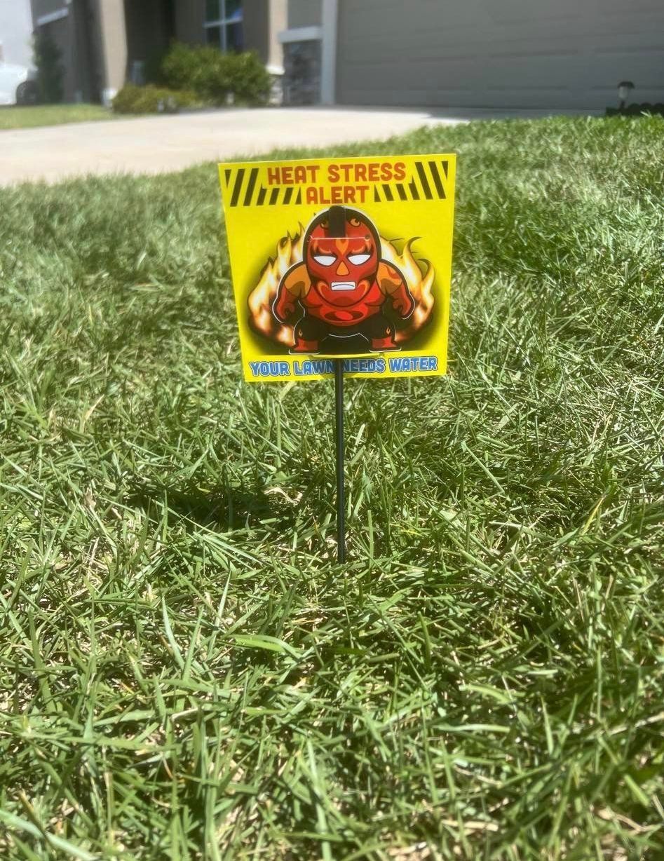 A sign that says `` heat stress alert '' is sitting in the grass.