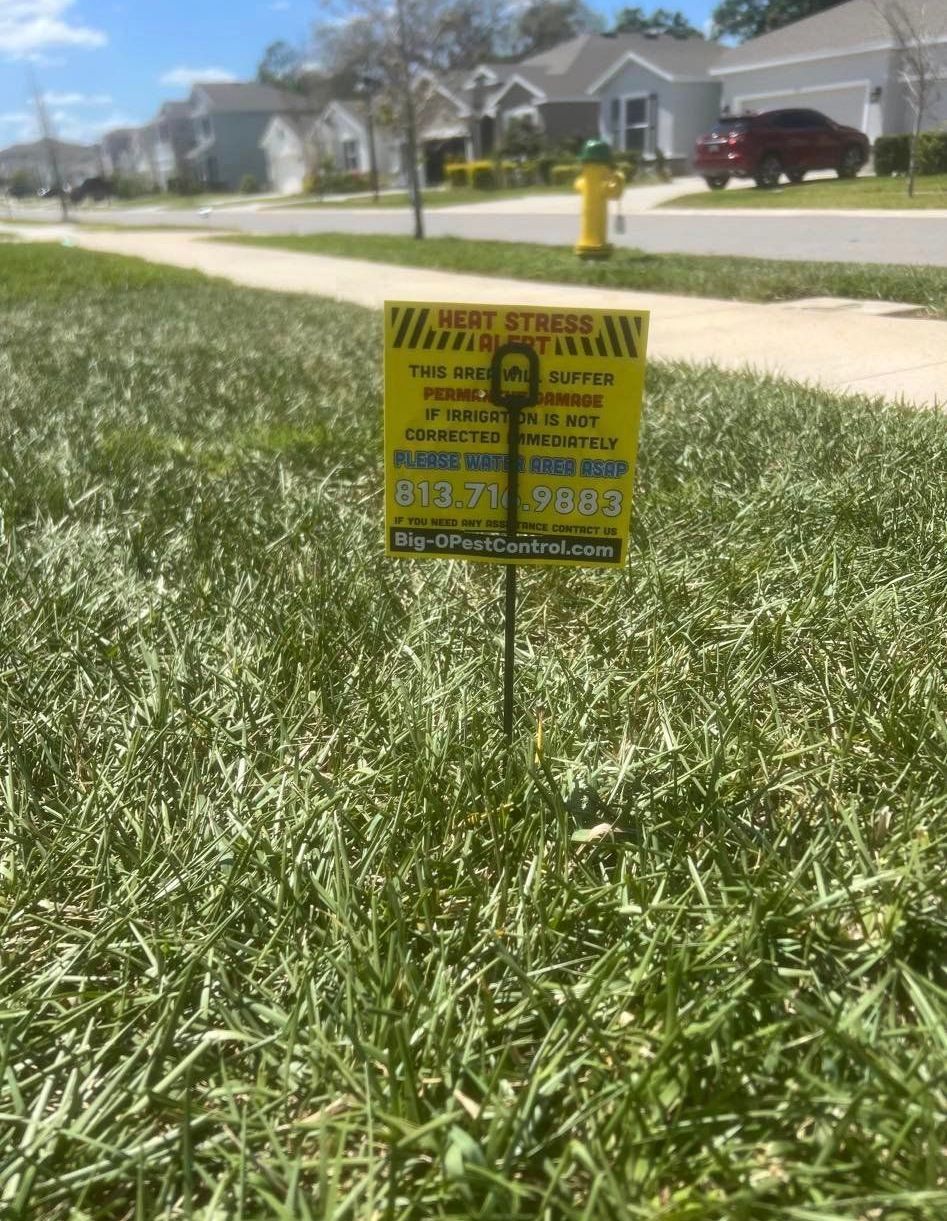 A yellow sign is sitting in the middle of a grassy field.