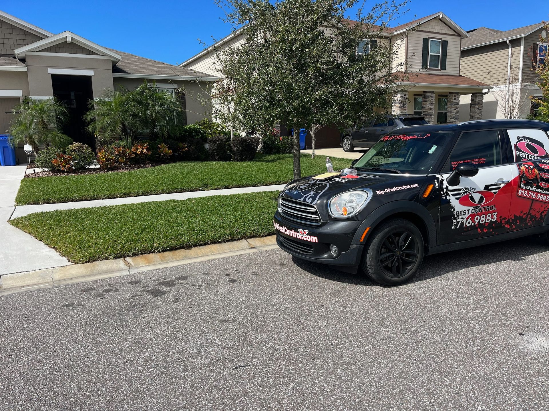 A black mini cooper is parked on the side of the road in front of a house.