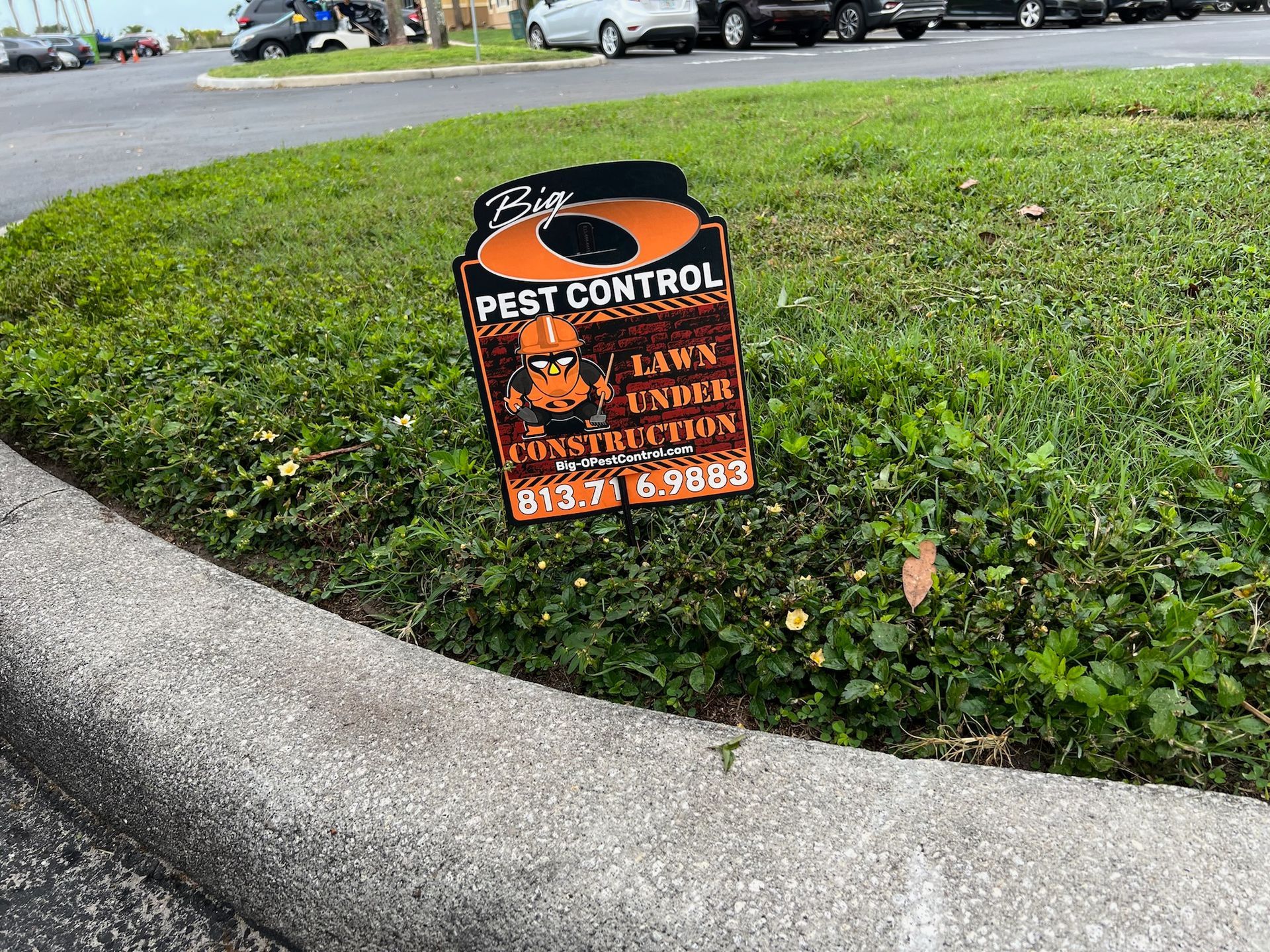 A sign for pest control is sitting on the side of the road.