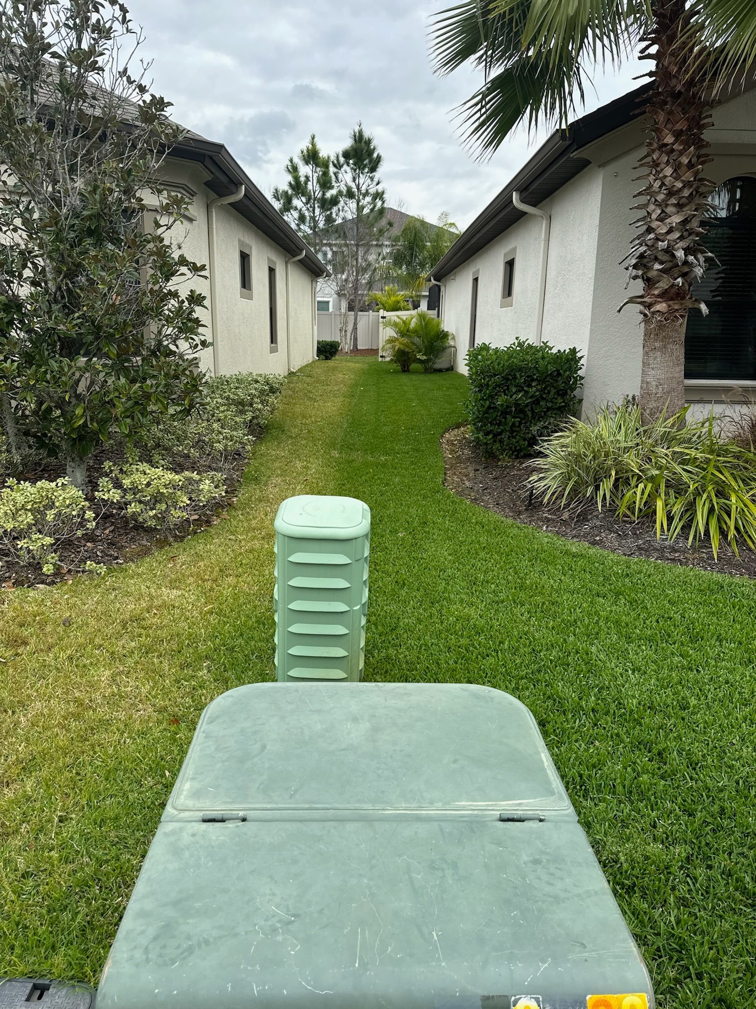 A lawn mower is cutting a lush green lawn in front of a house.