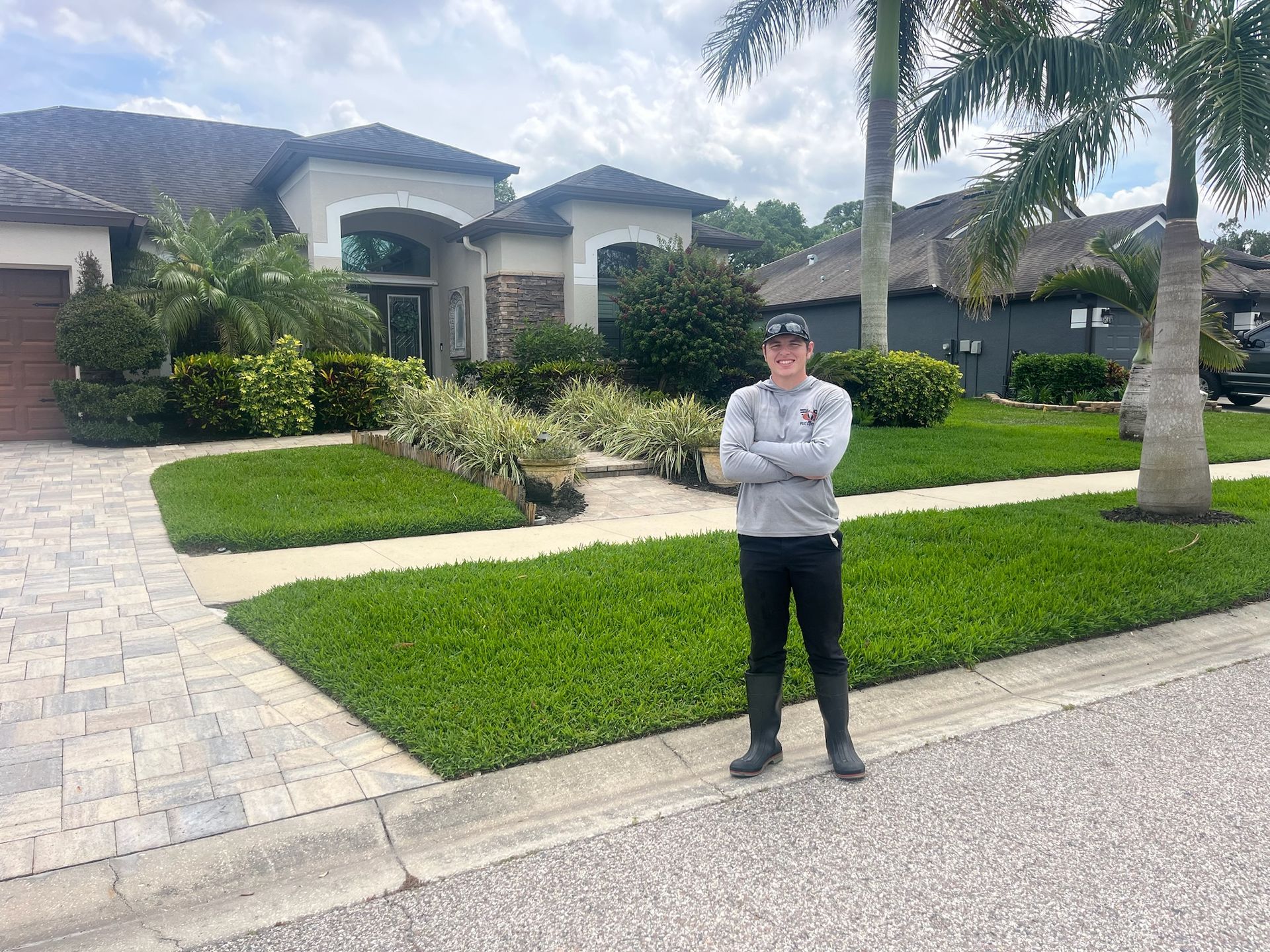 A man is standing in front of a house with his arms crossed.