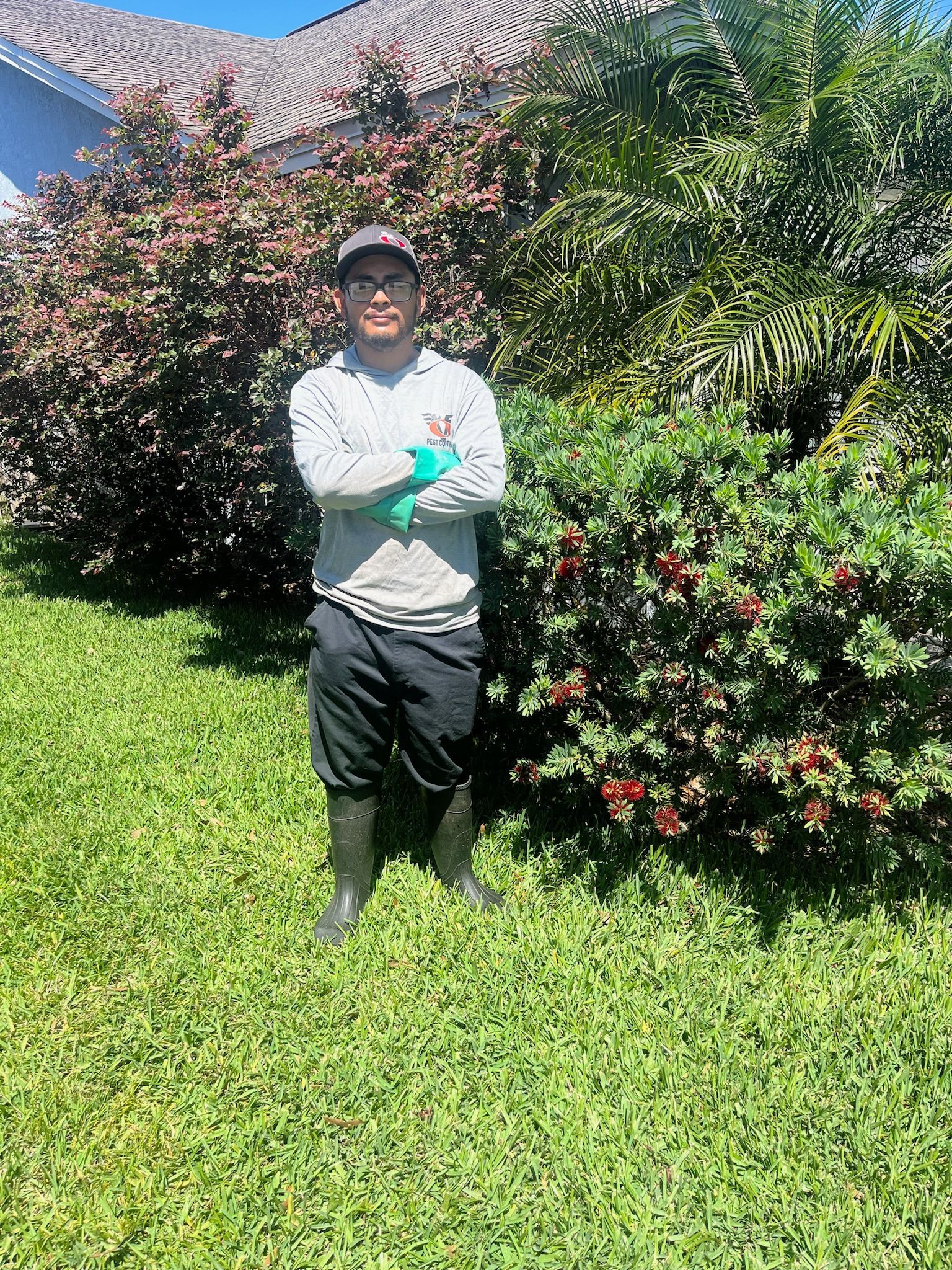 A man is standing in the grass in front of a bush.