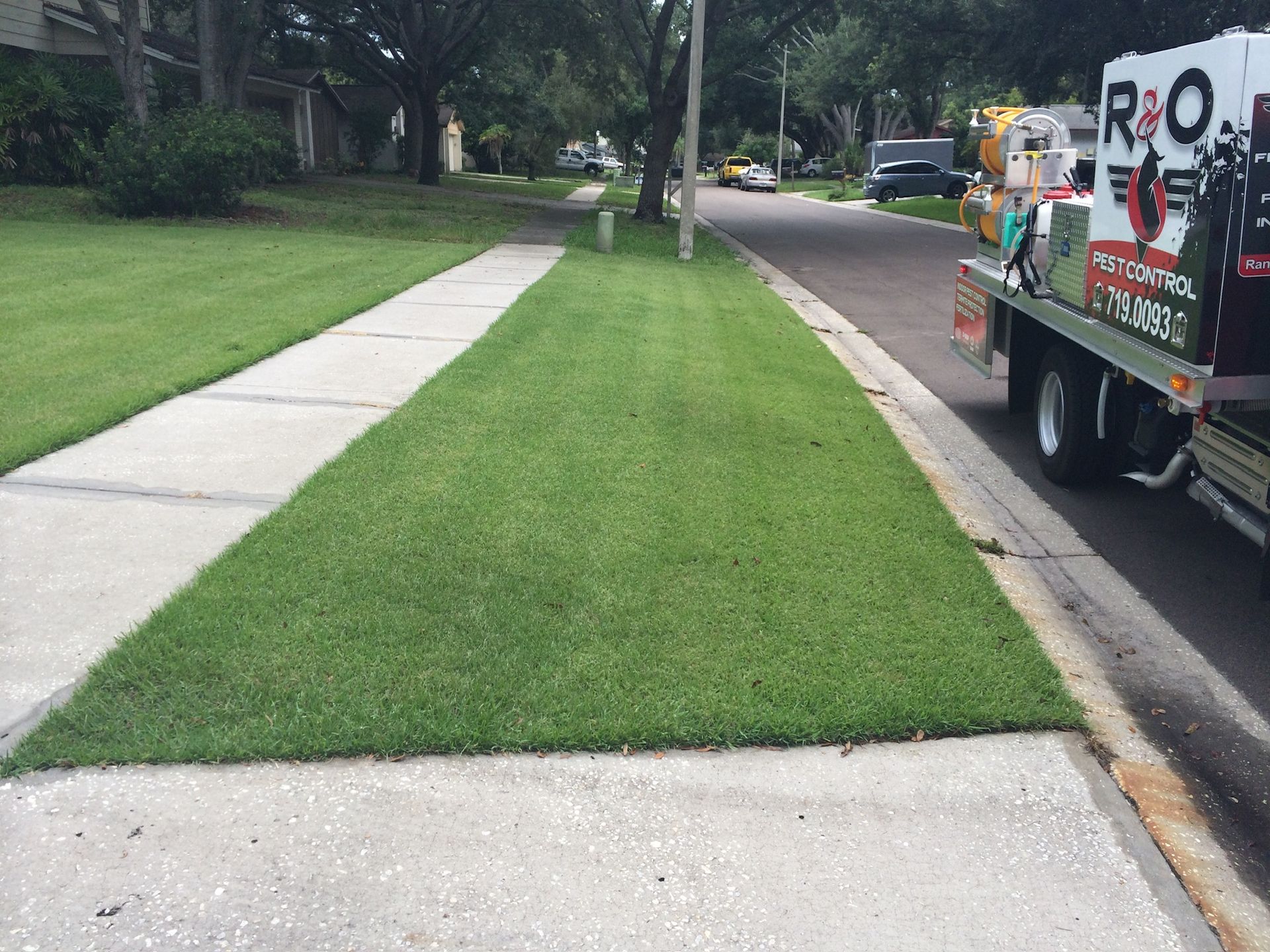 A tow truck is parked on the side of the road next to a lush green lawn.