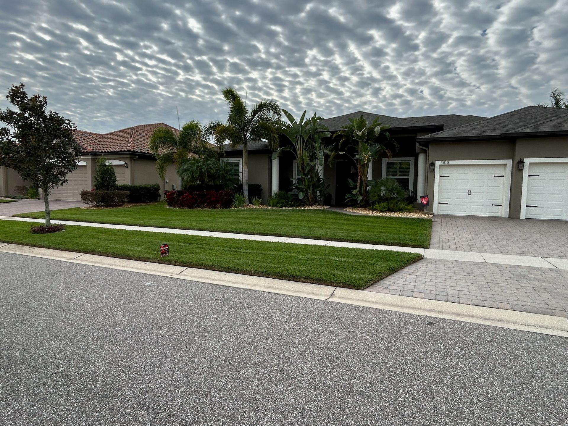 A house with two garages and a lush green lawn