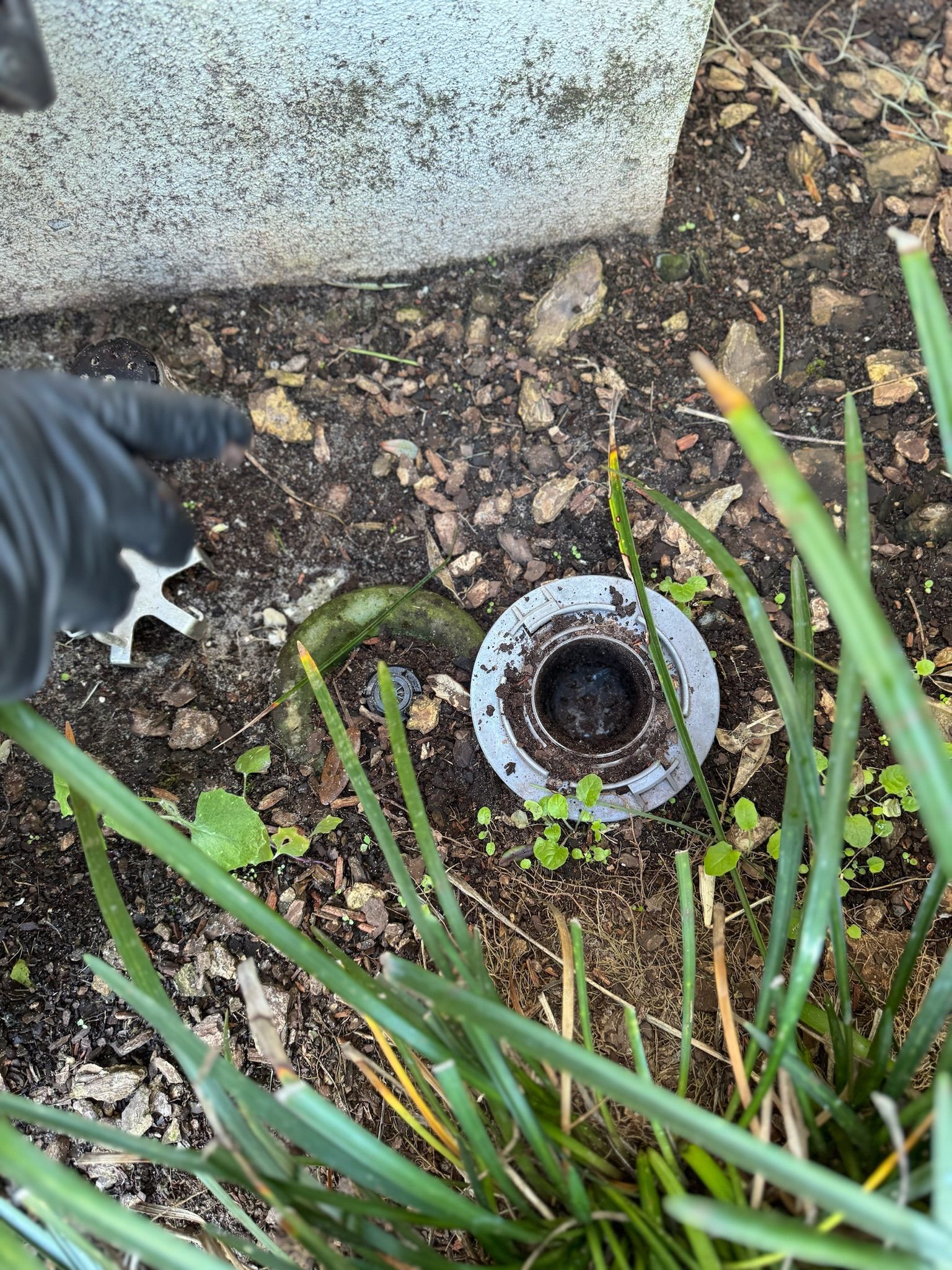 A person is cleaning a drain hole in the ground.