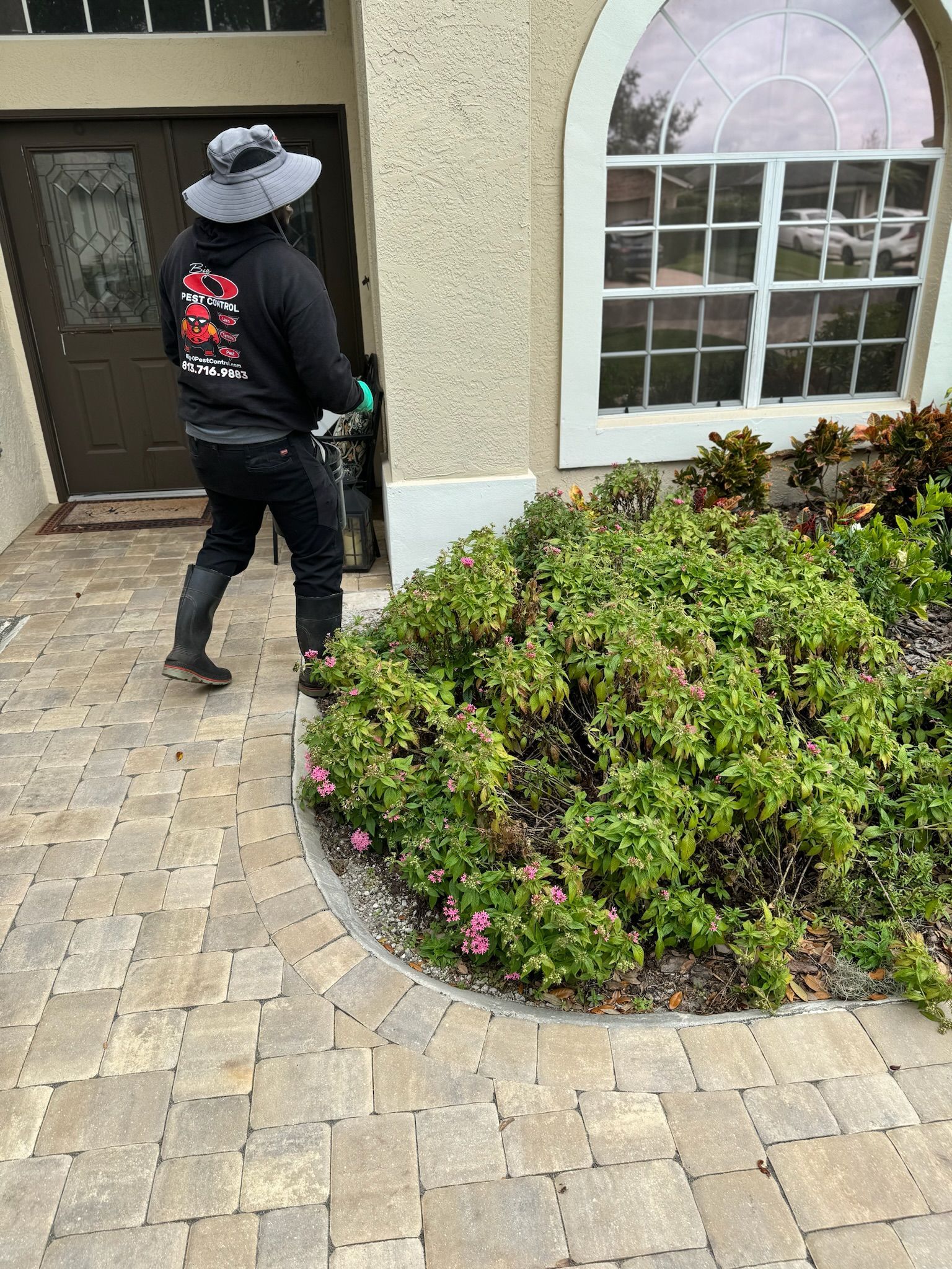 A man wearing a hat is standing in front of a house.