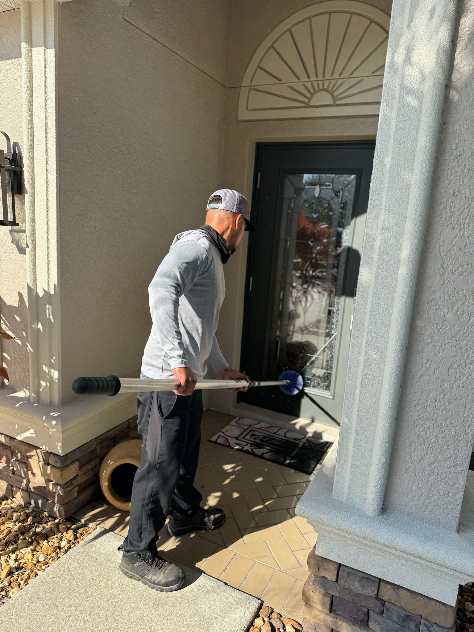 A man is standing in front of a house holding a shovel.